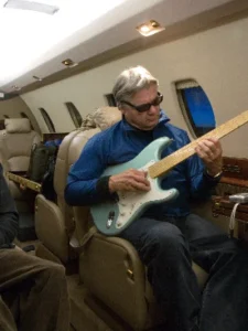 Men playing guitar on a plane